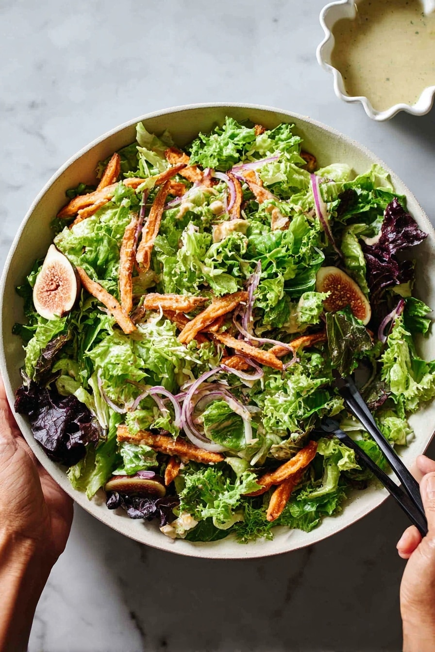 A large white bowl filled with a mixed green salad made up of several layers of leafy greens including light green lettuce, darker green spinach, and some purple-tinted leaves spread all over. Orange crispy strips are scattered throughout the leafy greens adding a crunchy texture, along with thin slices of red onion which add thin touches of purple. There is one half of a fig visible on the right side of the bowl adding a soft yellow and deep purple color. Two black chopsticks held by two woman's hands are positioned at the bottom sides of the bowl, ready to mix the salad. In the upper right corner, a white scalloped dish contains a creamy light dressing. The whole scene is set on a white marbled surface. photo taken with an iphone --ar 2:3 --v 7 - Fig Salad with Roasted Sweet Potatoes, Chickpeas, and Tahini Dressing, healthy fig salad, roasted sweet potato salad, vegan chickpea salad, tahini dressing recipes, nutritious veggie salads