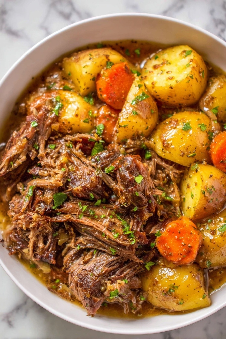 The image shows a white bowl filled with a stew-like dish made of two main layers: the bottom layer has brownish shredded meat with a glossy texture, scattered with small pieces of green herbs. The top layer has soft, yellowish potato chunks and bright orange carrot pieces mixed with the meat, all coated in a light brown sauce. The bowl is set on a white marbled surface. Photo taken with an iphone --ar 2:3 --v 7 - Ultimate Slow Cooker Pot Roast, slow cooker pot roast, easy pot roast recipe, hearty comfort food, tender beef dinner