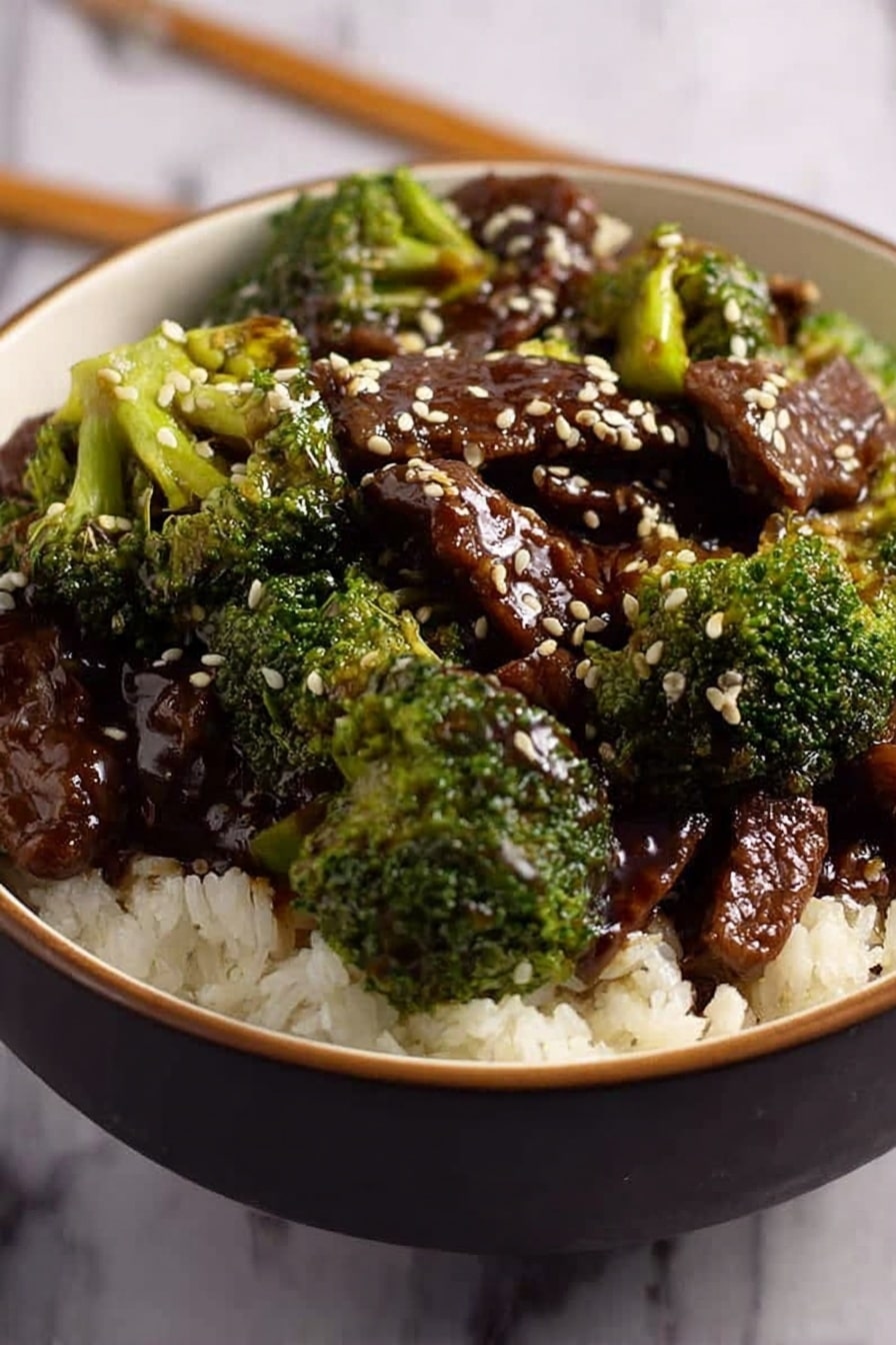 A white bowl filled with a bed of white rice at the bottom, topped with bright green broccoli florets and brown pieces of beef in a thick, shiny dark sauce. White sesame seeds are scattered over the beef and broccoli, adding small white specks. The bowl is on a white marbled surface, and a pair of chopsticks rests nearby. The textures contrast between the fluffy rice, tender beef, and crisp broccoli. Photo taken with an iphone --ar 2:3 --v 7 - Pressure Cooker Beef and Broccoli, quick beef stir-fry, healthy pressure cooker dinner, homemade beef broccoli dish, easy weeknight beef recipes