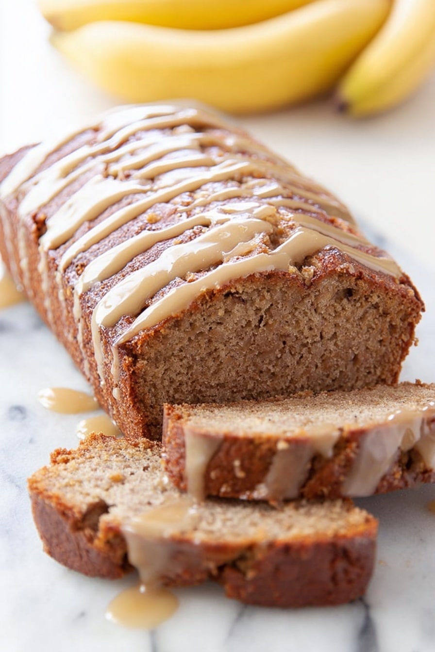 This image shows a loaf of dark chocolate cake with a cracked top, covered in a light caramel sauce that drips over the sides. The loaf is placed on a white surface with a white marbled texture. In the background, there are two whole yellow bananas and a white cup partly showing a light brown drink inside. The scene is bright and simple, focusing on the rich cake and creamy sauce. photo taken with an iphone --ar 2:3 --v 7 - Dulce de Leche Banana Bread, banana bread with dulce de leche, moist banana bread recipes, caramel banana bread, easy banana bread with dulce de leche