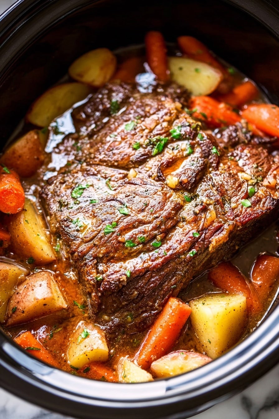 A close-up view of a slow cooker filled with a large browned meat roast as the top layer, its surface textured and seasoned with a shiny glaze and small green herb pieces sprinkled on it. Beneath and around the meat are soft, cooked carrot chunks in bright orange and light yellow potato pieces, all partially covered in rich brown juices that fill the cooker. The whole scene sits on a white marbled surface. Photo taken with an iphone --ar 2:3 --v 7 - Ultimate Slow Cooker Pot Roast, slow cooker pot roast, easy pot roast recipe, hearty comfort food, tender beef dinner
