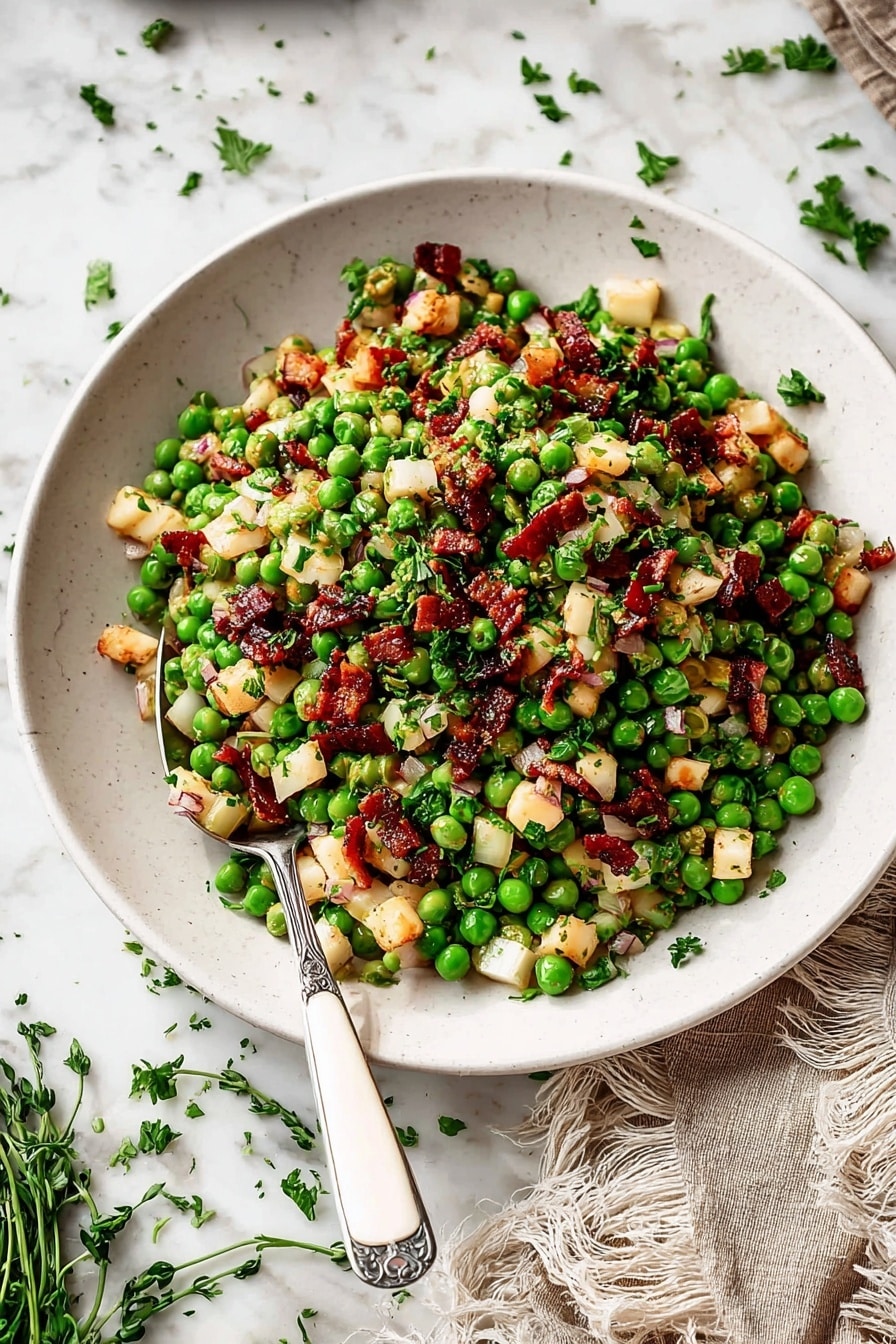 The image shows a white plate filled with a salad made of three main layers: the bottom layer is a mix of small bright green peas giving a fresh and lively look, the middle layer includes small light beige cubes and thin pale pink onion slices spread evenly, and the top layer features small dark red-brown cubes scattered all over. Garnished with bits of chopped green herbs, the dish has a varied texture of soft peas, crunchy onions, and firm cubes. A silver spoon with a white handle rests inside the plate on the left side. The plate is set on a white marbled surface with some scattered green herb leaves around and a beige cloth napkin with fringed edges at the bottom right corner. The photo taken with an iphone --ar 2:3 --v 7 - Thanksgiving Peas with Pear and Pancetta, holiday side dishes with peas and pear, easy Thanksgiving vegetable sides, savory pear and pancetta sides, festive holiday vegetable recipes