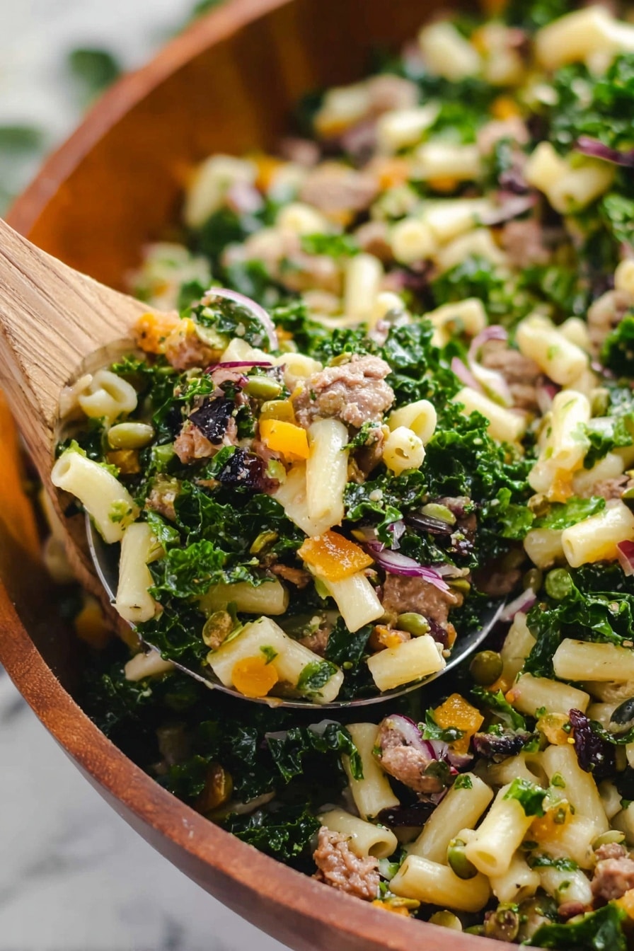 The image shows a close-up of a salad mix being lifted with a large spoon. The salad has small pale yellow pasta tubes as the main base, mixed with bright green kale pieces and some small browned cooked meat chunks. There are bits of orange vegetable, possibly roasted, and small pieces of purple onion. Dark green pumpkin seeds and some tiny dried dark red bits are scattered throughout the mix. The background has a white marbled surface, and the full salad is in a wooden bowl. photo taken with an iphone --ar 2:3 --v 7 - Fall Harvest Pasta Salad, autumn pasta salad, cranberry pasta salad, healthy fall pasta dish, easy fall pasta recipe