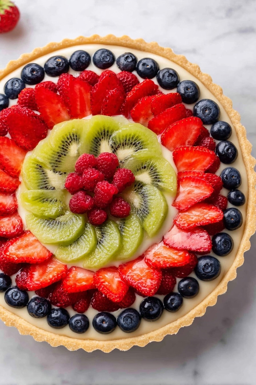 A fruit tart with multiple colorful layers sits on a white marbled surface. The bottom layer is a golden, slightly crimped crust. On top of the crust is a creamy white filling. Arranged in a circular pattern on the cream are three rings of fresh fruits: a center slice of green kiwi; the first ring consists of bright red raspberries; the second ring is made of dark blue blueberries; and the outer ring has sliced red strawberries with their inner, pale parts facing up, following the round shape of the tart. Photo taken with an iphone --ar 2:3 --v 7 - French Fruit Tart, French Fruit Tart recipe, fruit tart dessert, elegant dessert recipe, homemade fruit tart