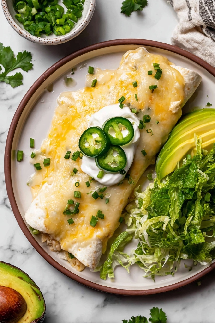 A speckled round plate with a brown rim holds a cheesy rolled enchilada covered in melted white and yellow cheese with chopped green onions sprinkled on top. A white dollop of sour cream sits in the center of the enchilada, topped with three thin slices of dark green jalapeño and small pieces of cilantro. To the right of the enchilada, there are thin slices of light green avocado resting on a bed of shredded dark green lettuce that fills the bottom right part of the plate. The plate sits on a white marbled surface with scattered cilantro leaves, half a dark green avocado with a brown seed, and a small white bowl filled with chopped green onions visible nearby. photo taken with an iphone --ar 2:3 --v 7 - White Chicken Enchiladas with Rotisserie Chicken, easy chicken enchiladas, creamy green chili enchiladas, weeknight chicken dinner, cheesy chicken enchiladas