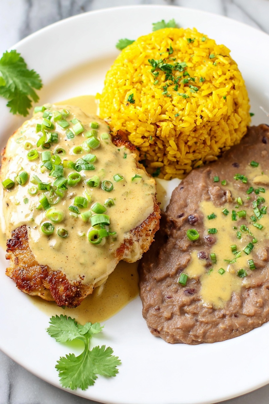 Easy Chori Pollo Recipe (Chicken with Chorizo and Cheese Sauce) Recipe 5 A white plate holds a meal with three main parts: on the left, a piece of golden-brown cooked meat topped with a creamy light yellow sauce sprinkled with chopped green onions and small herbs; in the middle right, there is a mound of bright yellow rice with a slightly rough texture and some green herb bits mixed in; at the bottom right, a smooth brown bean mixture spread in a thick layer, with some light yellow sauce drizzled over it, also sprinkled with green onions and herbs. Fresh cilantro sprigs decorate the edges of the plate. The plate sits on a white marbled surface. photo taken with an iphone --ar 2:3 --v 7 - Easy Chori Pollo, Chicken with Chorizo and Cheese Sauce, smoky chorizo chicken, cheesy chicken chorizo dish, quick chori pollo recipe