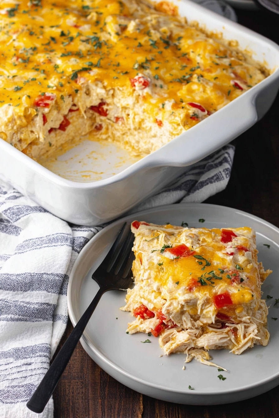 The image shows a white rectangular baking dish filled with a layered casserole. The bottom layer appears to be creamy and light yellow, topped with shredded chicken mixed with small pieces of red bell pepper. Above this is a thick layer of melted yellow and white cheese sprinkled lightly with green herbs. A square piece has been taken out, showing the soft, creamy texture of the layers inside. Next to the dish is a white plate holding the square piece of the casserole, with a black fork resting on the plate. The scene is set on a dark wooden surface partially covered by a white and blue striped cloth, with the baking dish and plate placed on a white marbled textured surface. Photo taken with an iphone --ar 2:3 --v 7 - Salsa Verde Chicken Casserole, chicken casserole with salsa verde, quick chicken casserole recipes, easy Mexican chicken bake, cheesy chicken casserole