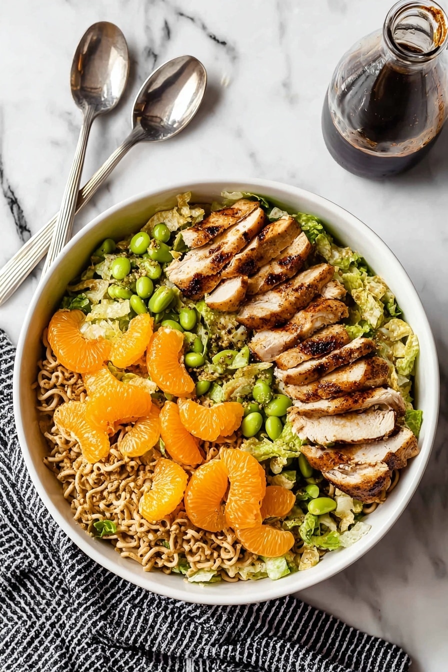 A white bowl filled with a salad showing three main layers: the bottom layer is chopped green lettuce, the middle layer has light brown crunchy noodle pieces scattered throughout, and the top layer contains several slices of grilled brown and white chicken laid evenly, with bright orange mandarin orange segments and some green edamame beans spread on top. The bowl sits on a white marbled surface with a silver fork and spoon placed above it, and a glass bottle of dark dressing to the right, with a black and white striped cloth partly visible under the bowl. Photo taken with an iphone --ar 2:3 --v 7 - Chinese Chicken Salad, Chinese Chicken Salad recipe, healthy Chinese chicken salad, easy Chinese salad, crunchy chicken salad