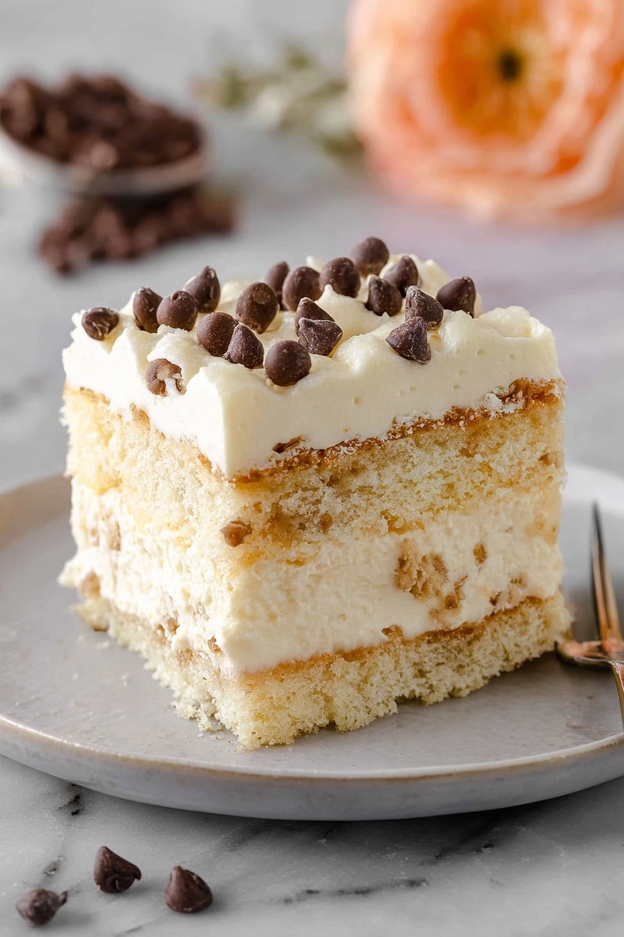 Tiramisu Cannoli Recipe 5 A square piece of creamy layered dessert sits on a white plate with a simple design. The dessert has three visible layers: light brown sponge cake at the bottom, a thick middle layer of pale cream mixed with sponge bits, and a top layer of smooth cream sprinkled with small dark chocolate chips. The cake layers look soft and moist, while the cream layers appear smooth and thick. The background has a soft focus with a peach-colored flower and some scattered chocolate chips on a white marbled texture. Photo taken with an iphone --ar 2:3 --v 7 - Tiramisu Cannoli, Italian dessert recipes, no-bake desserts, creamy mascarpone recipes, coffee layered desserts